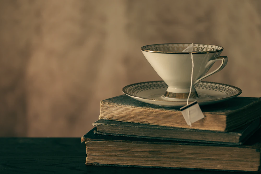 A white ceramic cup beside the pages of an open book